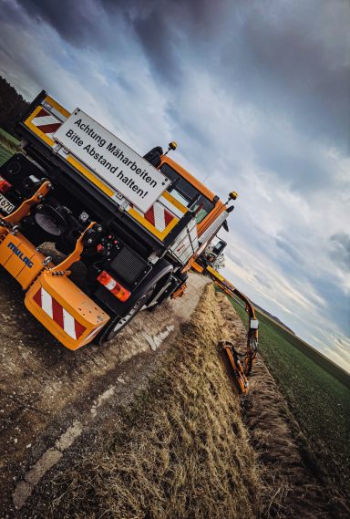 Mulchjarbeiten und Grasmahd in einem Solarpark zwischen den Solarmodulen